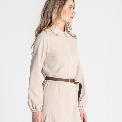 Mulher de perfil veste vestido bege com cinto castanho