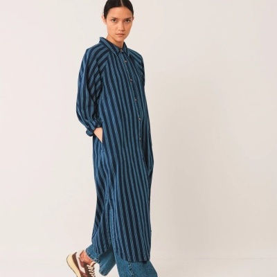 Vestido comprido azul com riscas verticais pretas e botão frontal, usado por mulher em fundo branco