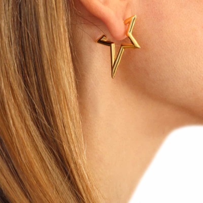 Brinco dourado em forma de estrela geométrica numa orelha