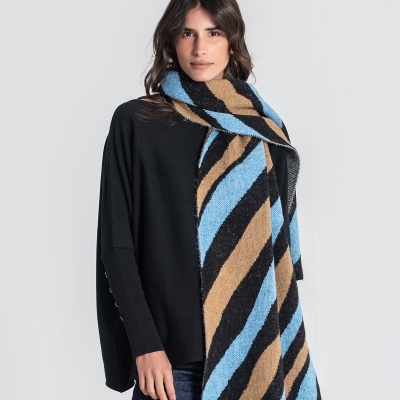 Mulher com cachecol xadrez azul castanho preto, camisola preta e calças de ganga