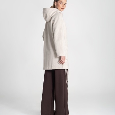 Mulher de costas com casaco bege, calças largas castanhas e sapatos de salto.