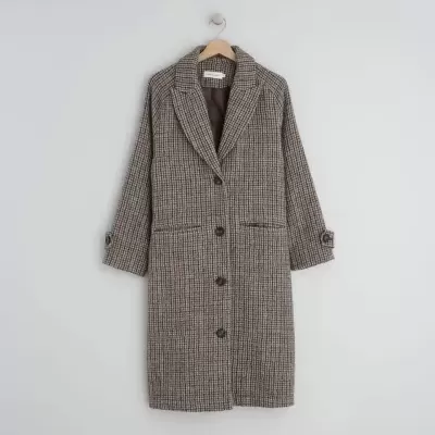 Casaco comprido xadrez castanho pendurado na parede