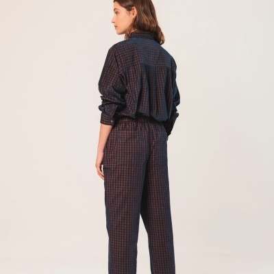 Mulher de costas vestindo conjunto de fato de treino xadrez azul e vermelho com calças e camisa de manga comprida.