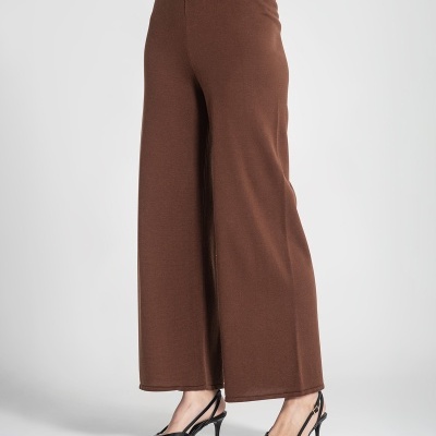 Calças largas castanhas com cintura elástica e botão dourado, usadas com sapatos pretos de salto