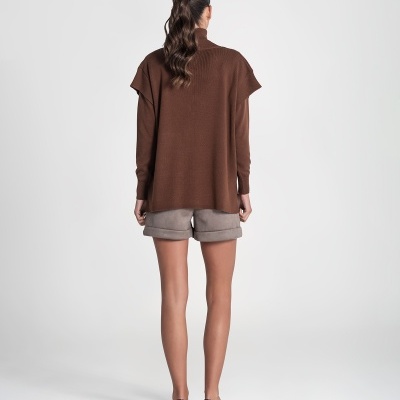 Mulher de costas com camisola castanha, shorts cinzentos e sandálias pretas