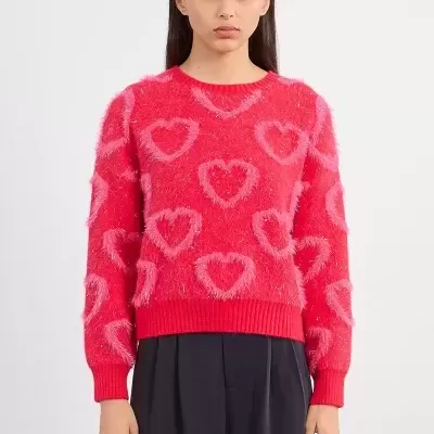 Mulher a vestir camisola vermelha felpuda com corações cor-de-rosa e calças pretas largas em fundo neutro