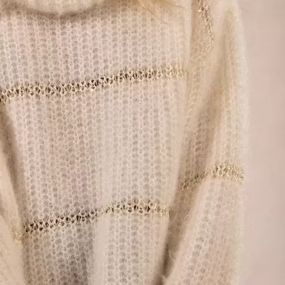 Blusão de malha creme com riscas douradas e decote alto.