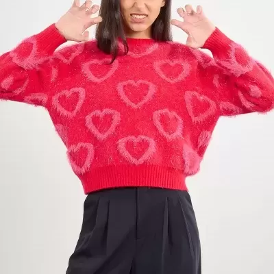 Mulher com camisola rosa de malha com corações e calças pretas