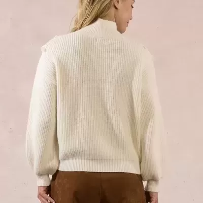 Mulher de costas com camisola branca de malha e calções castanhos