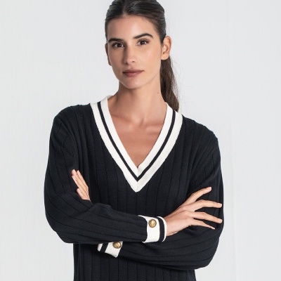 Sweater preto canelado com decote em V e punhos brancos com botões dourados.