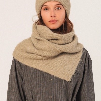 Mulher com gorro e echarpe bege de malha felpuda e roupa cinzenta com cinto