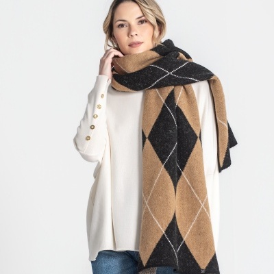 Mulher com cachecol xadrez castanho e preto, camisola branca e jeans azuis sobre fundo branco