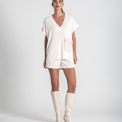 Mulher com roupa creme e botas brancas em fundo branco