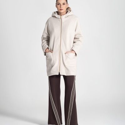 Mulher usando casaco bege claro com capuz e calças castanhas com riscas brancas