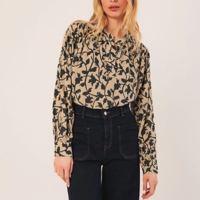 Mulher vestindo blusa bege com padrão de flores pretas e calças jeans pretas de cintura alta