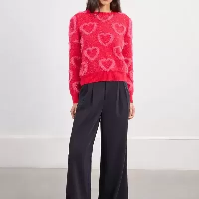 Mulher com camisola vermelha com corações rosa e calças largas pretas