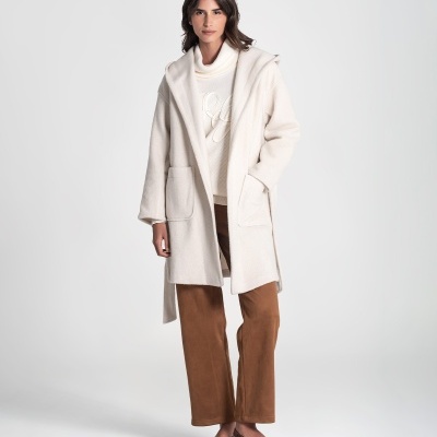 Mulher com casaco creme, camisola gola alta creme, calças castanhas e sapatilhas castanhas