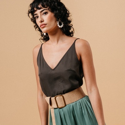 Mulher com vestido preto e saia verde com cinto bege