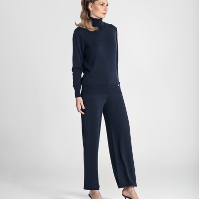 Conjunto de malha azul escuro com camisola de gola subida e calças largas usado por mulher em estúdio