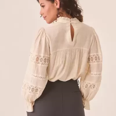 Blusa feminina creme com detalhes rendados e calça preta.