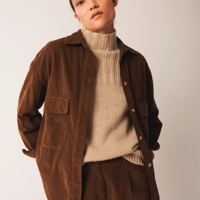 Conjunto feminino de camisa e calças castanhas em veludo com camisola bege de gola alta.