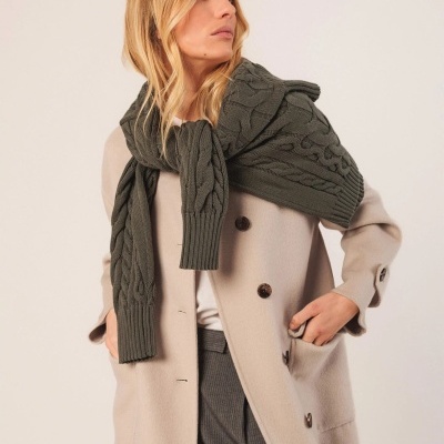 Mulher a usar casaco bege e cachecol de malha verde escura com padrão de tranças