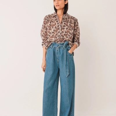 modelo a usar calças largas de ganga azul e camisa estampada castanha e bege