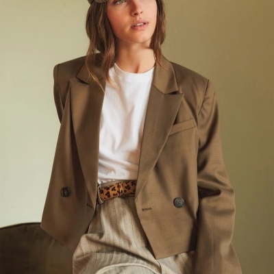 Mulher veste blazer castanho, t-shirt branca, calças bege e cinto animal print