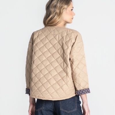 Casaco bege acolchoado com bainha da manga roxa e calças jeans escuras