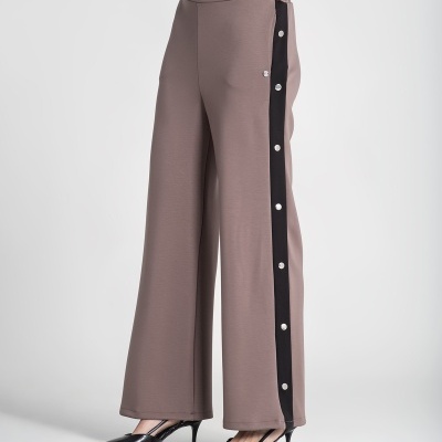 Calças largas castanhas com faixa preta e botões de pressão laterais usadas com sapatos pretos