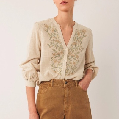 Blusa bege claro com bordados florais e botões brancos