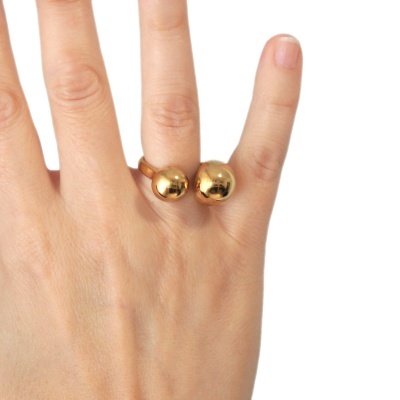 Anel de metal dourado com duas esferas nas pontas no dedo médio