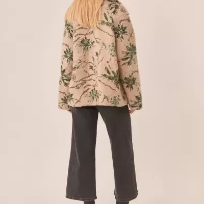 Casaco felpudo bege flores verdes, calças pretas largas e botins pretos com salto.