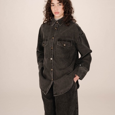 Camisa de ganga preta oversized com bolsos e botões, usada com calças largas pretas.