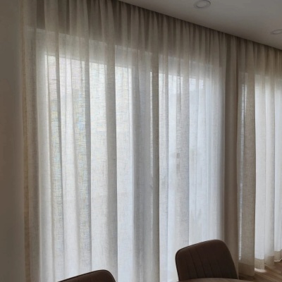 Cortinas transparentes brancas numa janela ampla com cadeiras castanhas escuras