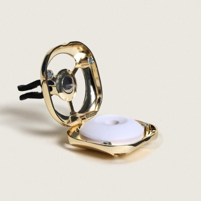 Estojo dourado aberto com componente branco no centro