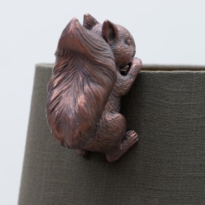 Figura decorativa de esquilo em bronze presa a tecido verde-oliva