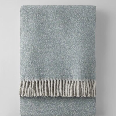 Manta azul claro com franja branca dobrada em fundo branco