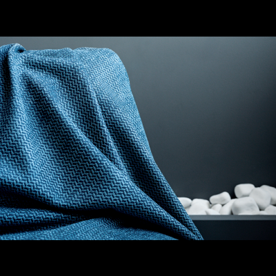 Manta azul com padrão ziguezague, pedras brancas e fundo cinza