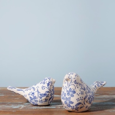 Duas estatuetas de pássaros em cerâmica branca decoradas com padrão floral azul
