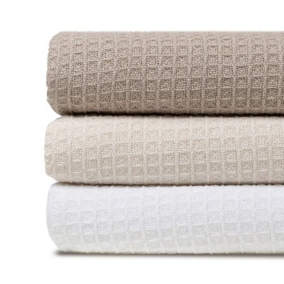 Três toalhas de banho dobradas em branco e tons de bege com padrão de waffle