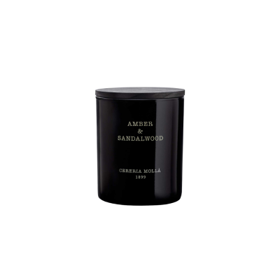 vela perfumada em recipiente de vidro preto com texto dourado e tampa de madeira