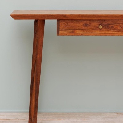 Mesa de madeira castanho escuro com gaveta e puxador dourado em parede cinza