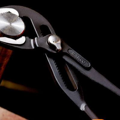 Alicate de pressão preto com punhos laranja segurando peça metálica cilíndrica prateada