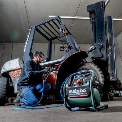 Homem a reparar empilhador com compressor Metabo numa oficina
