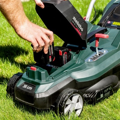 Cortador de relva elétrico Metabo verde escuro com rodas cinza e detalhes vermelhos em relva