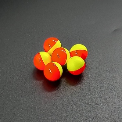 Seis flutuadores de pesca bicolores em amarelo e vermelho sobre superfície preta
