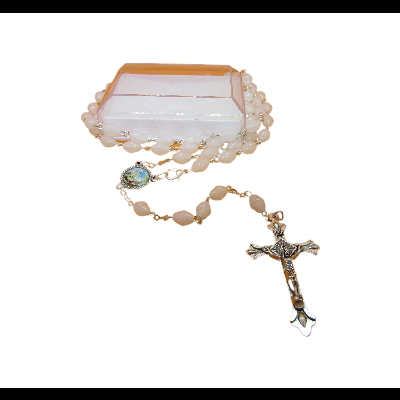 Terço com contas creme translúcidas, medalhão azul e cruz prateada sobre superfície branca.