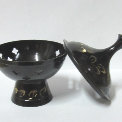 Peças de cerâmica preta com detalhes dourados sobre superfície branca.