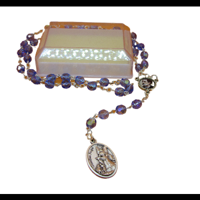 Terço com contas roxas e medalha religiosa sobre base translúcida